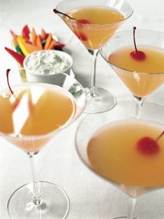 three glasses filled with drinks sitting on top of a table