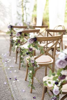 rows of wooden chairs with purple flowers on them and greenery growing up the back