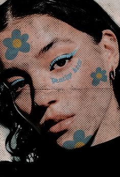 a woman with blue and yellow flowers painted on her face is holding scissors to her nose