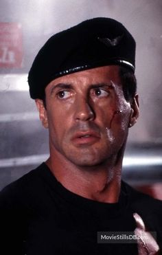 a close up of a person wearing a black shirt and hat with his eyes open