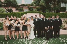 a group of people posing for a photo in front of a building with white flowers