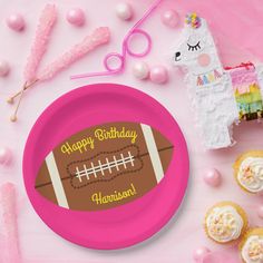 a pink plate with a football on it next to cupcakes and other decorations