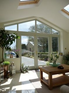 a living room filled with furniture and lots of windows next to a patio area covered in potted plants