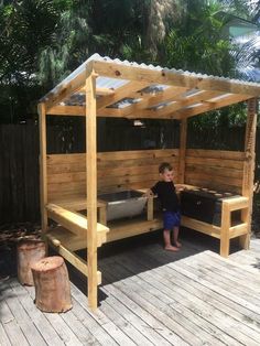 a little boy that is standing in front of a gazebo with some plants on it