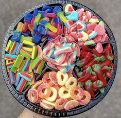 a person holding up a plate full of colorful candies and pretzel rings