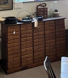 an old dresser has many drawers and plates on it