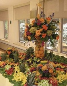 an arrangement of flowers and fruit on a table