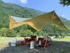 a tent set up in the middle of a field with buckets and barrels under it