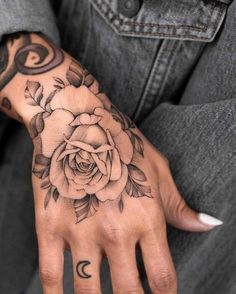 a person's hand with a rose tattoo on it