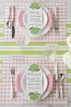 the place setting is laid out with pink and green napkins, silverware, and flowers