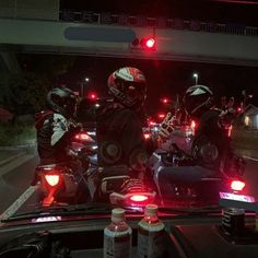 several motorcyclists riding in the back of a truck at night with their lights on