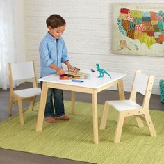 a young boy is playing with his toy table and chair set in the living room