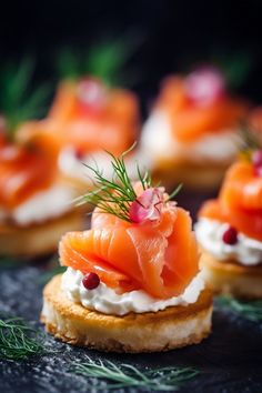 small crackers with smoked salmon and cream cheese on them are arranged on a black surface