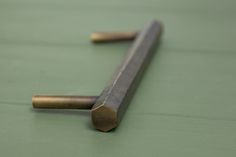 a pair of brass handles on a green surface with one end pointing up to the other side