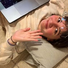 a woman laying on the floor next to a laptop