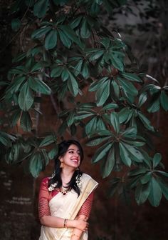 a woman in a white sari standing under a tree