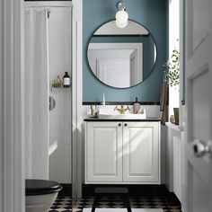 a bathroom with a black and white checkered floor, blue walls and a round mirror above the sink