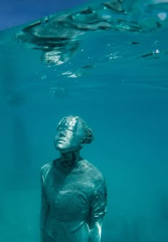 a statue under the water with its head in the air