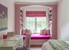 a bedroom with pink walls and built - in bookshelves has a window seat