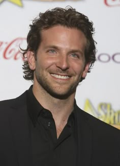 a man smiling and wearing a black suit