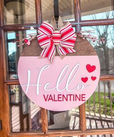 a pink hello valentine door hanger with red and white bows on it's front