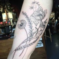 a woman's leg with flowers and leaves tattoo on the side of her arm