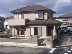 a house with a fence in front of it and cars parked on the side of the road