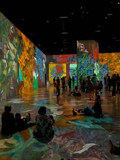 people are sitting on the floor in front of colorful paintings