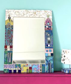 a mirror sitting on top of a purple shelf next to a lamp and a blue wall