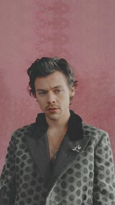 a man in a black and white polka dot jacket looking at the camera with a serious look on his face