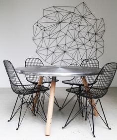 a table with four chairs around it and a metal sculpture behind it on the wall