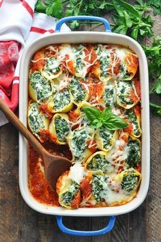 a casserole dish with spinach, cheese and sauce in it on a wooden table