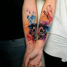 two people holding hands with colorful tattoos on their arms and arm, one has a skull