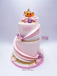 a three tiered cake is decorated with pink and purple ribbons, an orange clown on top