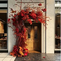 an entrance to a restaurant decorated with autumn leaves and flowers in front of the door