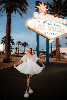 a woman posing in front of the welcome to fabulous las vegas sign with her dress on