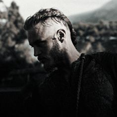 a bearded man with braids on his head looking at something in front of him