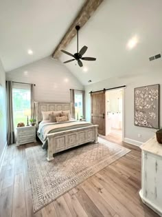 a large bedroom with hardwood floors and white walls, has a ceiling fan in the corner