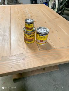 two cans of paint sitting on top of a wooden table