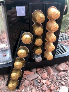 an old fashioned coffee maker with lots of cups in front of it on the ground