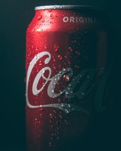 a can of coca - cola with water droplets on the side, in front of a black background