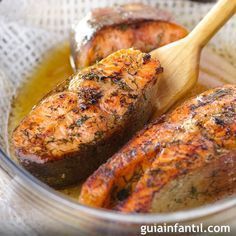 two cooked meats in a glass bowl with a wooden spoon on the side and olive oil