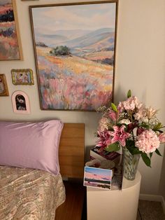 a bed room with a neatly made bed and pictures on the wall above it that have flowers in vases