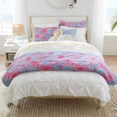 a white bed with pink and blue comforter