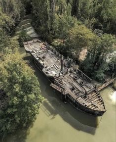 an old boat is sitting in the water next to some trees and other things around it