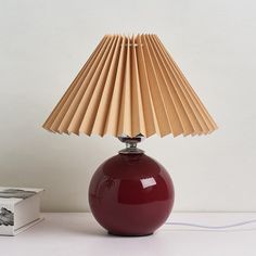 a red lamp sitting on top of a table next to a box and a book