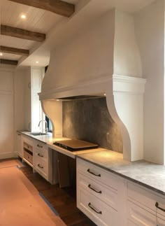 a large kitchen with white cabinets and an oven in the center, along with wood flooring