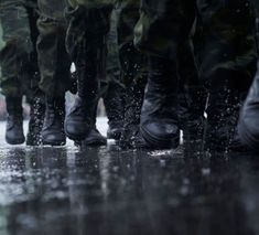 many soldiers are standing in the rain with their boots on