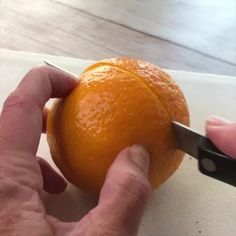 a person cutting an orange with a pair of scissors