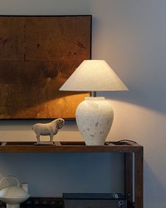 a table with a lamp on it and a dog figurine next to it